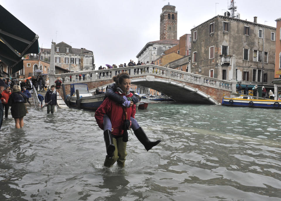 People walk in high water near the Ponte delle Guglie in Venice, Italy, Thursday, Nov. 1, 2012. High tides have flooded Venice, leading Venetians and tourists to don high boots and use wooden walkways to cross St. Mark's Square and other areas under water. Flooding is common this time of year and Thursday's level that reached a peak of 55 inches (140 centimeters) was below the 63 inches (160 centimeters) recorded four years ago in the worst flooding in decades. (AP Photo/Luigi Costantini)