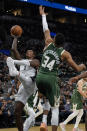 San Antonio Spurs' Lonnie Walker IV (1) tries to shoot over Milwaukee Bucks' Giannis Antetokounmpo (34) during the first half of an NBA basketball in San Antonio, Texas, Saturday, Oct. 23, 2021. (AP Photo/Chuck Burton)