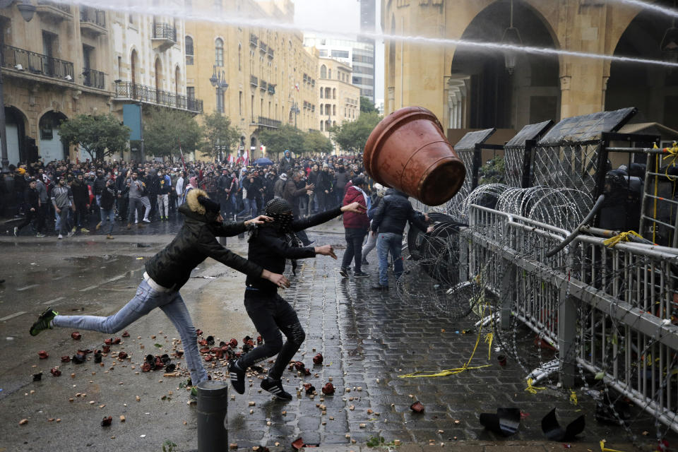 Anti-government demonstrators clash with riot police at a road leading to the parliament building in Beirut, Lebanon, Saturday, Jan. 18, 2020. Riot police fired tears gas and sprayed protesters with water cannons near parliament building to disperse thousands of people after riots broke out during a march against the ruling elite amid a severe economic crisis. (AP Photo/Hassan Ammar)