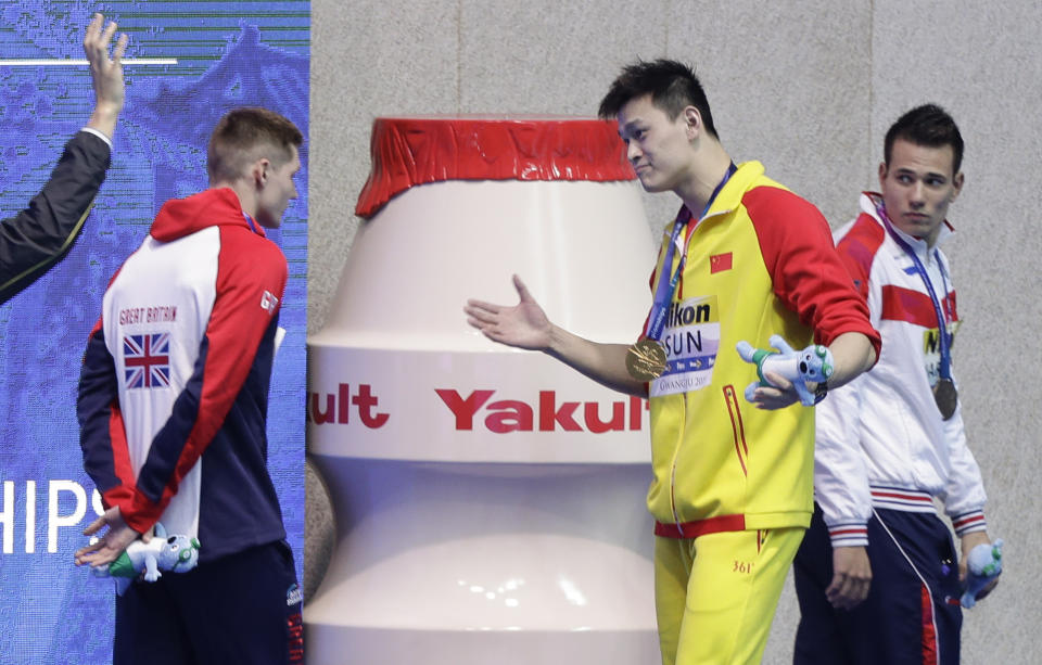 FILE - In this Tuesday, July 23, 2019 file photo, gold medalist China's Sun Yang gestures to Britain's bronze medalist Duncan Scott, left, following the medal ceremony in the men's 200m freestyle final at the World Swimming Championships in Gwangju, South Korea. One of China’s biggest Olympic stars will undergo a rare public trial of a doping case on Friday, Nov. 15, 2019 with his 2020 Tokyo Games place at stake. Three-time gold medalist swimmer Sun Yang is facing a World Anti-Doping Agency appeal in Switzerland that seeks to ban him for up eight years. (AP Photo/Mark Schiefelbein, File)