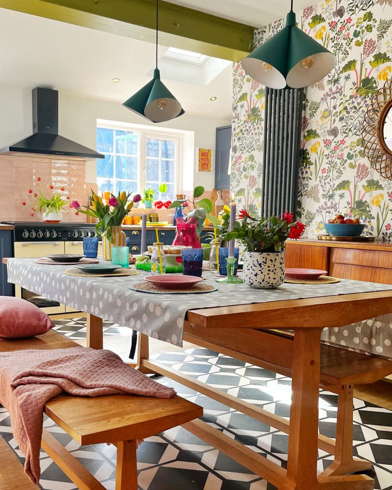 Green pendant lamps over wooden dining table with colorful dining setting.