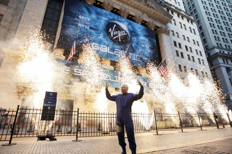 FILE - In this Monday, Oct. 28, 2019 file photo, Sir Richard Branson, founder of Virgin Galactic, poses for a photo outside the New York Stock Exchange as fireworks are exploded before his company's IPO. In 2020, NASA Administrator Jim Bridenstine said space is currently a $400 billion market, including satellites. Opening up spaceflight to paying customers, he said, could expand the market to $1 trillion. (AP Photo/Richard Drew)