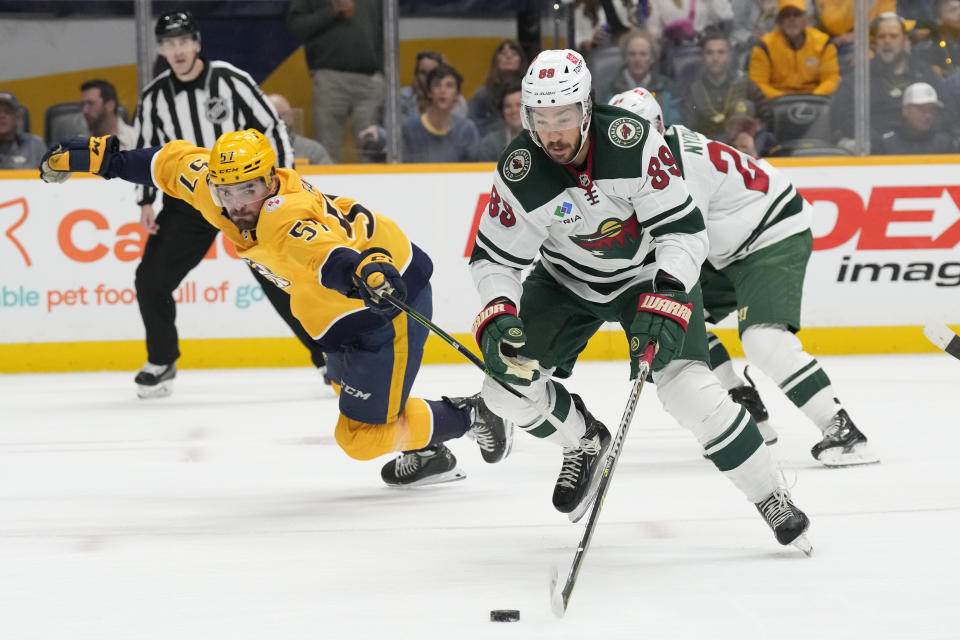 Minnesota Wild center Frederick Gaudreau (89) moves the puck against Nashville Predators defenseman Dante Fabbro (57) during the first period of an NHL hockey game Thursday, April 13, 2023, in Nashville, Tenn. (AP Photo/Mark Humphrey)