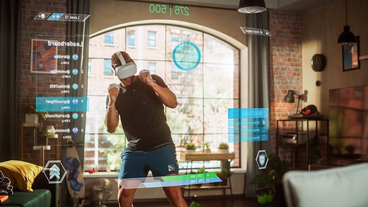 Man standing up and using a virtual reality headset and handheld controls in a living room.