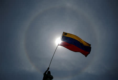 FILE PHOTO: An opposition supporter holds a Venezuelan flag during a rally against the government of Venezuela's President Nicolas Maduro and to commemorate May Day in Caracas Venezuela, May 1, 2019. REUTERS/Ueslei Marcelino