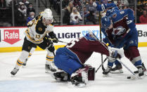 Boston Bruins center Charlie Coyle, left, looks on as Colorado Avalanche goaltender Darcy Kuemper, center, tries to collect the puck with the help of defenseman Cale Makar, right, in the second period of an NHL hockey game Wednesday, Jan. 26, 2022, in Denver. (AP Photo/David Zalubowski)