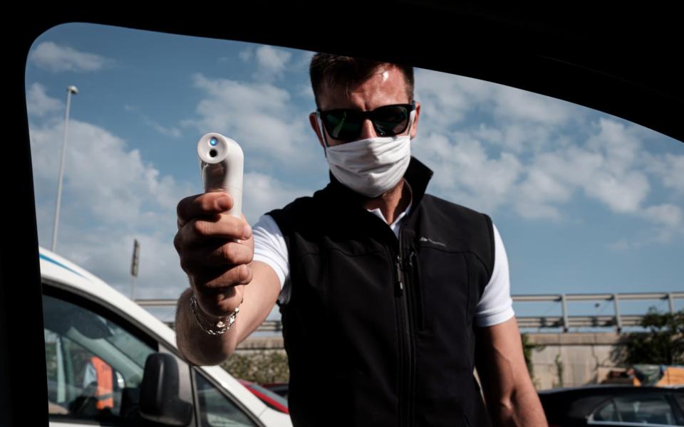 A worker takes the temperature of those travelling by ferry to the Italian island of Sardinia - MARZIO TONIOLO/REUTERS