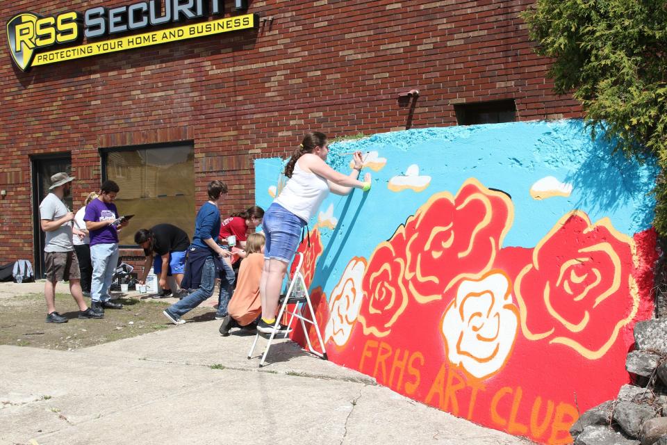 Ross High School art teacher Bradley Scherzer, left, works with members of the Art Club on an Ohio-themed mural, at the corner of North Front Street and North Street, near the fairgrounds.