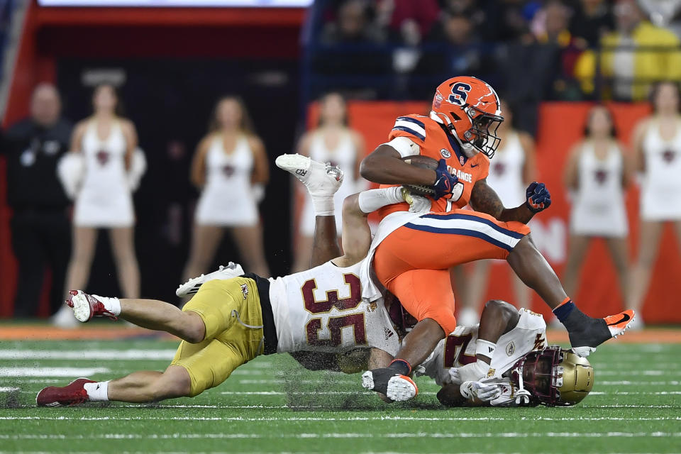Syracuse running back LeQuint Allen Jr., top, is tackled by Boston College defensive back John Pupel (35) and cornerback Amari Jackson (24) during the first half of an NCAA college football game in Syracuse, N.Y., Friday, Nov. 3, 2023. (AP Photo/Adrian Kraus)