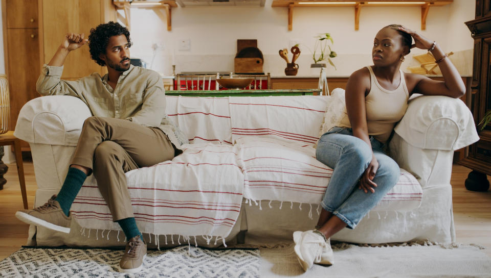 Two people sitting apart on a couch with tense body language