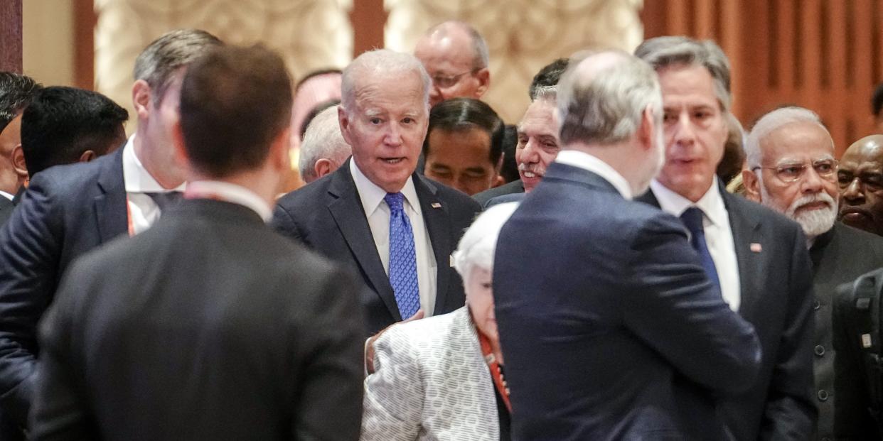 Biden visible amid group of men in suits, two in forefront with back to camera