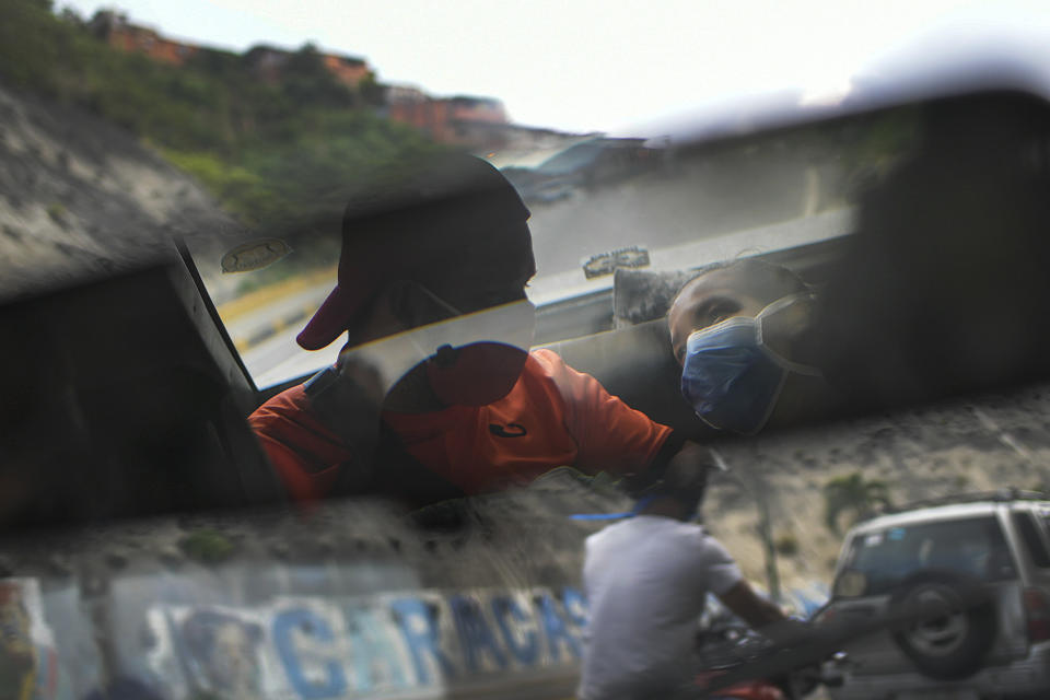 Reflejado en el espejo retrovisor, Leo Camejo se sienta con su pareja Ada Mendoza y su hija recién nacida Peyton mientras un amigo los lleva a casa después de ser dado de alta del hospital, en Caracas, Venezuela, el sábado 12 de septiembre de 2020. (AP Foto/Matias Delacroix)