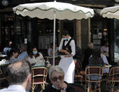 People sit on the Cafe de Flore terrace in Paris, Tuesday, June 2, 2020. Local Parisians are savoring their cafe au lait and croissants at the Left Bank's famed Cafe de Flore, or on the cobbled streets of the ancient Le Marais for the first time in almost three months. As virus confinement measures were relaxed Tuesday, cafes around France were allowed to reopen. (AP Photo/Christophe Ena)