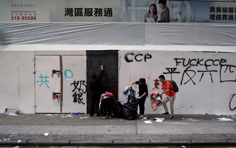 Bank workers clean the entrance of their bank branch which was vandalised during Sunday's anti-government protest in Hong Kong