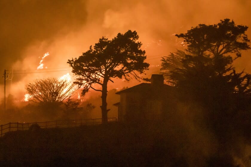 The Colorado Fire burns behind a house off Highway 1 near Big Sur, Calif., Saturday, Jan. 22, 2022. (AP Photo/Nic Coury)