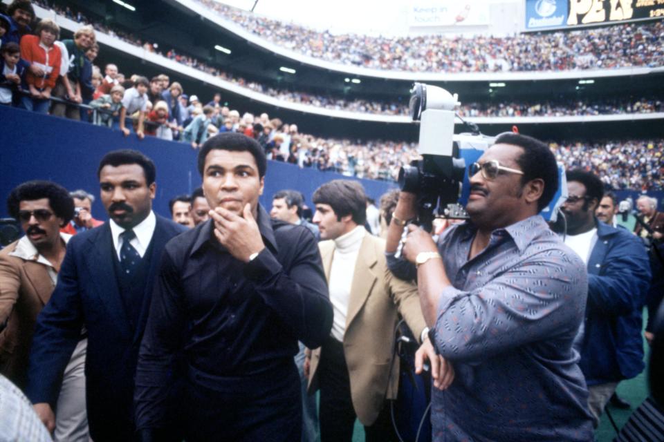 World Heavyweight Boxing Champion Muhammad Ali (c) is filmed as he walks out at Giants Stadium with his brother Rahaman (second l) to greet Pele before the Brazilian star's final match of his career  (Photo by Peter Robinson/EMPICS via Getty Images)