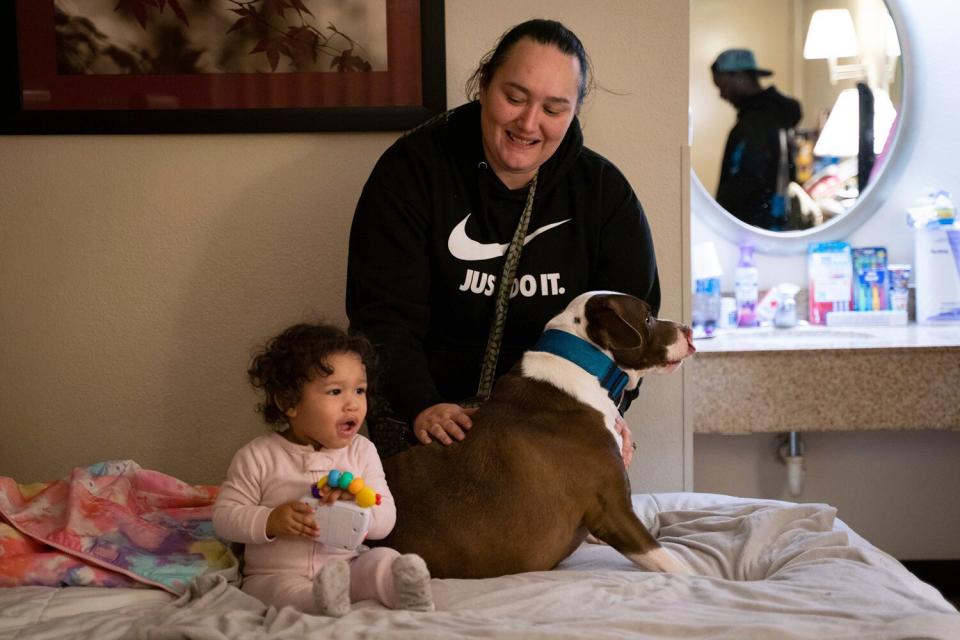 Janet Kelly, 40, and her daughter Shantel Kelly, 1, play with their dog named Blue at Red Roof Inn in Roseville on Monday, Feb. 27, 2023.