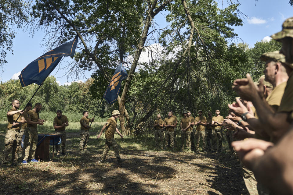 Soldiers of Ukraine's 3rd Separate Assault Brigade react as officers hand them the brigade emblems, near Bakhmut, the site of fierce battles with the Russian forces in the Donetsk region, Ukraine, Sunday, Sept. 3, 2023. (AP Photo/Libkos)