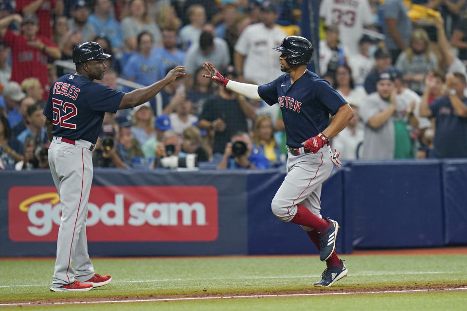 Boston Red Sox's Xander Bogaerts, right, is congratulated by third base coach Carlos Febles (52) after his solo home run against the Tampa Bay Rays during the third inning of Game 2 of a baseball American League Division Series, Friday, Oct. 8, 2021, in St. Petersburg, Fla. (AP Photo/Chris O'Meara)