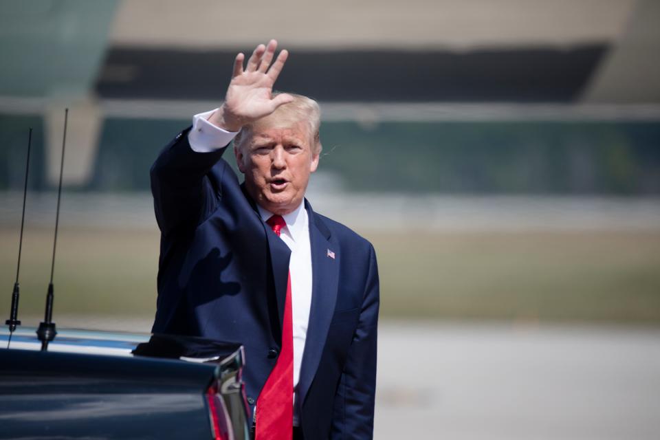 President Donald Trump waves at the media on the tarmac at Wright-Patterson Air Force base.