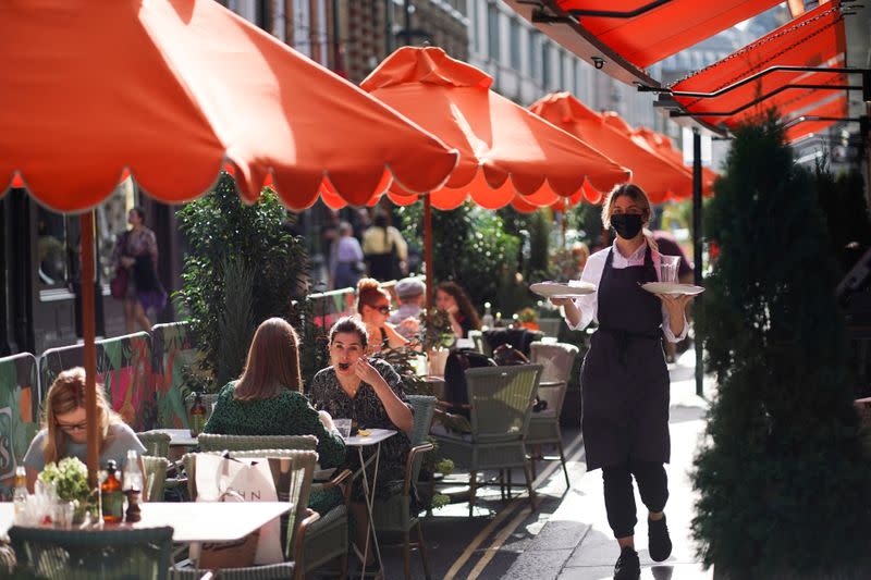 FILE PHOTO: People sit at tables outside restaurants in Soho, amid the coronavirus disease (COVID-19) outbreak, in London