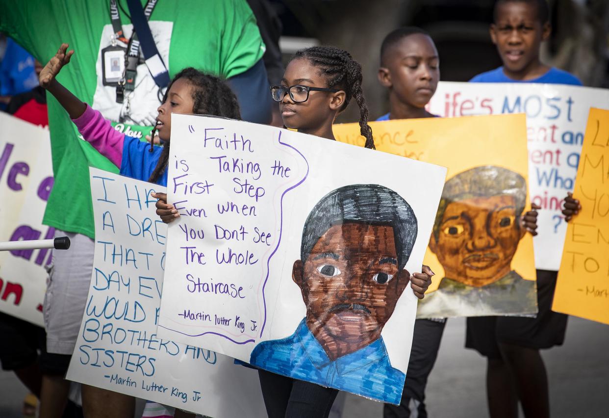 Children from Keep It Real Ministries carry Martin Luther King Jr. quotes on posters as they march along the parade route during the 42nd annual MLK Day Parade in downtown Lakeland.