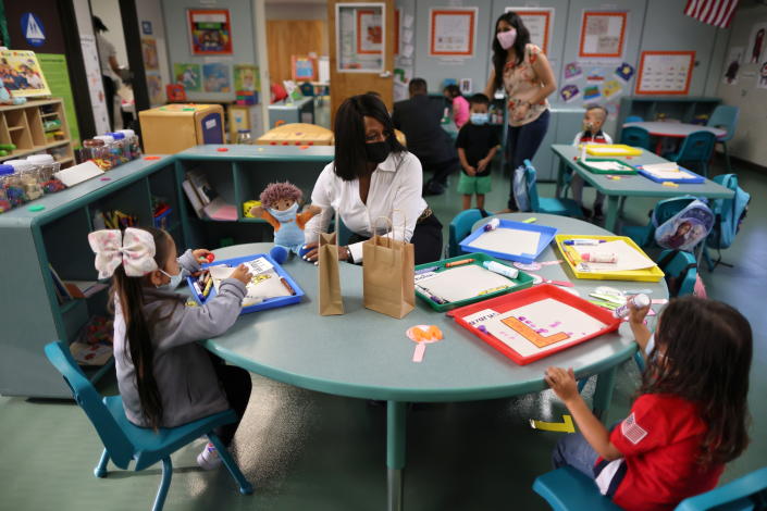 A teacher and students wear masks in a classroom.