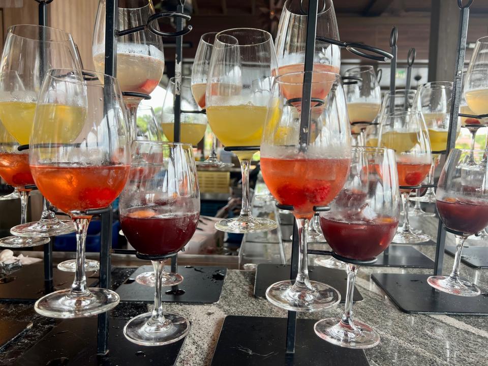 Multiple glasses of different sangrias in shades yellow, red, and purple.