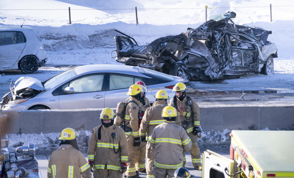 Emergency personnel stand next to demolished cars following a massive pileup involving numerous vehicles on the south shore of Montreal in La Prairie, Quebec, Wednesday, Feb. 19, 2020. (Paul Chiasson/The Canadian Press via AP)
