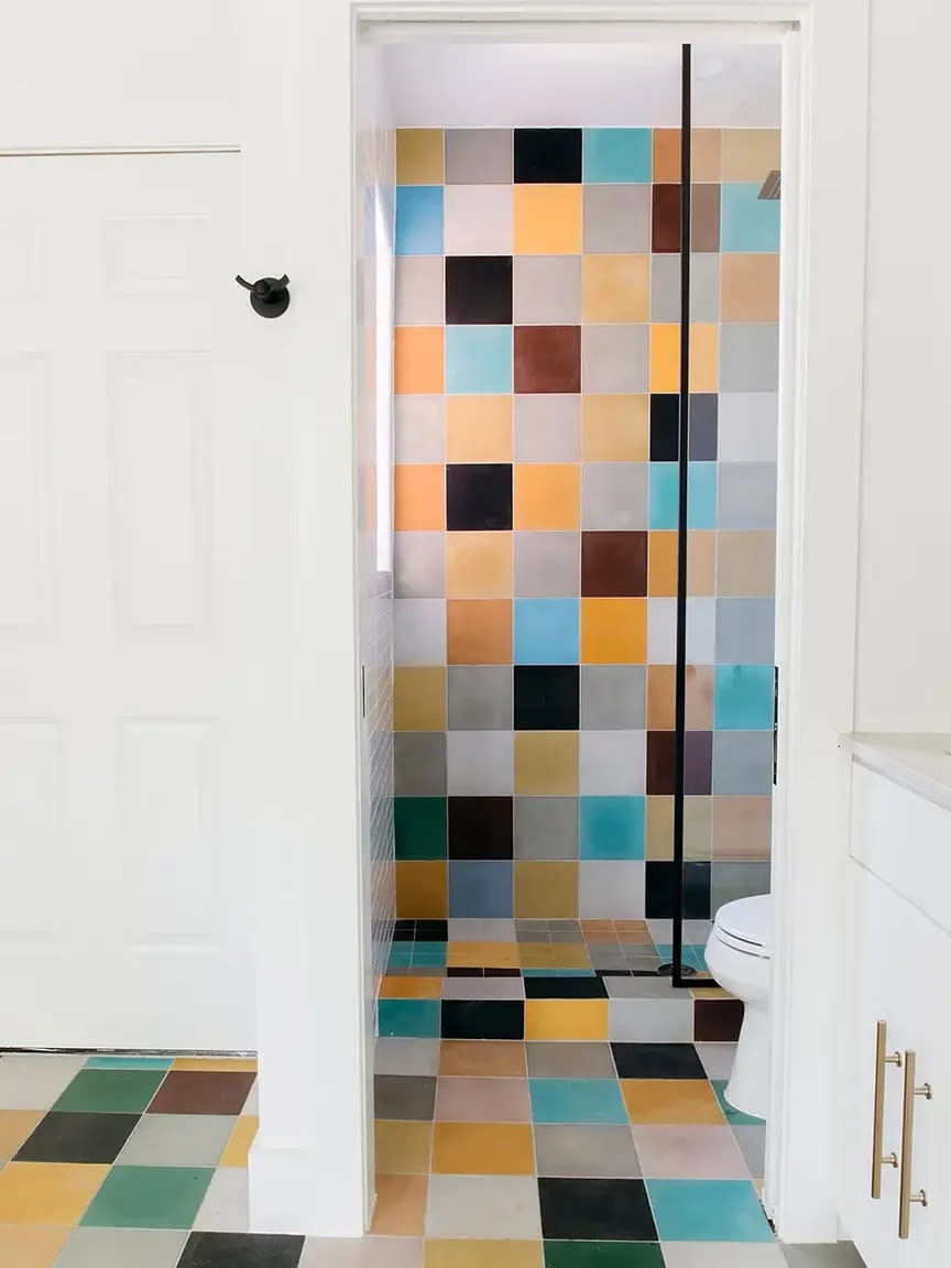 Bathroom with multi-color tile lining the wall and floor.