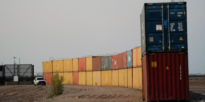 Border Patrol agents patrol along a line of shipping containers stacked near the border Tuesday, Aug. 23, 2022, near Yuma, Ariz.