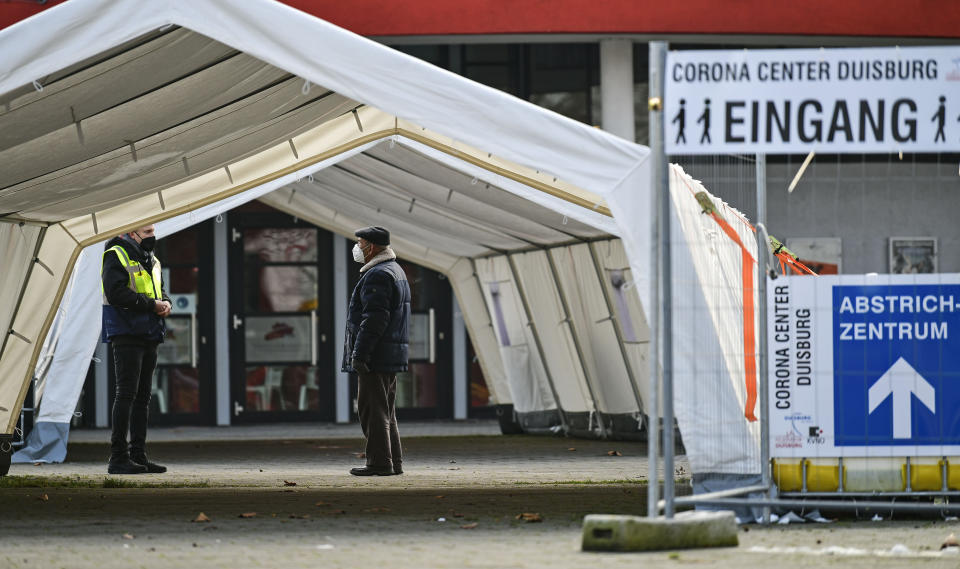 FILE - In this Monday, Jan. 25, 2021 file photo, a man wearing a face mask asks for information at the Corona Center in Duisburg, Germany. The former Musical theater has been turned into a COVID-19 test and vaccination center. Thousands of elderly Germans faced online error messages and jammed up hotlines Monday as technical problems marred the start of the coronavirus vaccine campaign for over-80s in the country's most populous state. (AP Photo/Martin Meissner, File)