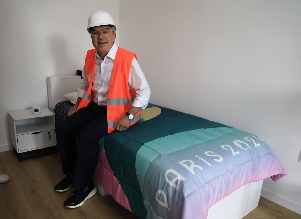 International Olympic Committee (IOC) president Thomas Bach sits on a bed as he visits the Athletes' village in Saint-Ouen-sur-Seine, outside Paris, Tuesday, July 25, 2023. (Pascal Rossignol/Pool via AP)