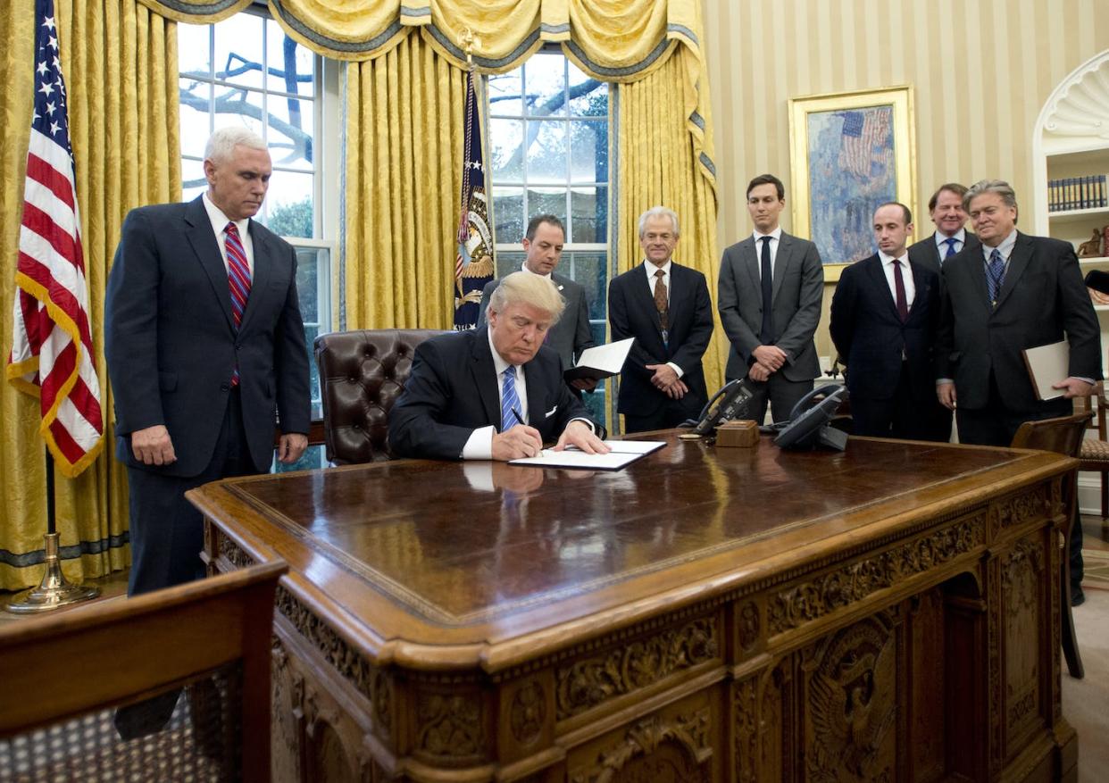 At a January 2017 executive order signing, adviser Peter Navarro is third from left behind Trump, while Steve Bannon is on the far right. <a href="https://www.gettyimages.com/detail/news-photo/president-donald-trump-signs-the-first-of-three-executive-news-photo/632489940" rel="nofollow noopener" target="_blank" data-ylk="slk:Ron Sachs - Pool/Getty Images;elm:context_link;itc:0;sec:content-canvas" class="link ">Ron Sachs - Pool/Getty Images</a>
