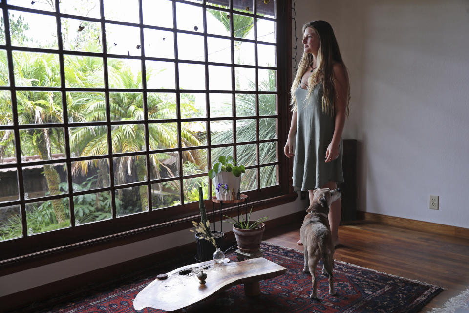 Lindsay Cloyd and her dog, Lily, stand inside their home, Tuesday, Nov. 29, 2022, in Hilo, Hawaii. (AP Photo/Marco Garcia)