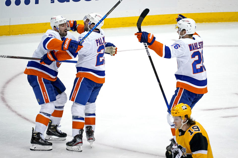 New York Islanders' Kyle Palmieri, center, celebrates with Nick Leddy (2) and Oliver Wahlstrom (26) after putting a shot over Pittsburgh Penguins goaltender Tristan Jarry for the game-winning goal in overtime in Game 1 of an NHL hockey Stanley Cup first-round playoff series in Pittsburgh, Sunday, May 16, 2021. The Islanders won 4-3. (AP Photo/Gene J. Puskar)