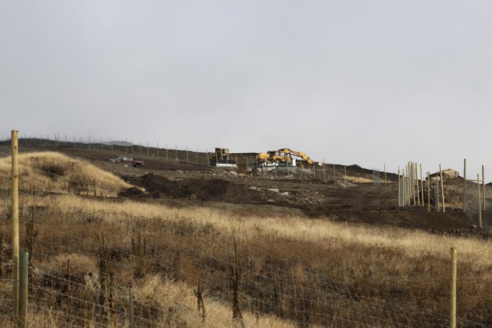 Construction machinery work within a fenced-off cherry orchard expansion site near Kelowna, British Columbia, on Dec. 7, 2023. Experts are concerned that the cherry orchard's expansion is impacting the mobility of animals that use a nearby wildlife corridor in an area under threat from urban sprawl and other development. (Aaron Hemens/IndigiNews via AP)