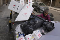 A man searches in trash dumpsters for recyclable items to resell next to cardboard voting booths that were used Sunday in the Lebanese parliamentary elections in Beirut, Lebanon, Monday, May 16, 2022. Lebanon's militant Hezbollah group and its allies suffered losses in this weekend's parliamentary elections, with preliminary results Monday showing some of their most vocal opponents picking up more seats and several of their traditional partners routed out of the legislature. (AP Photo/Hassan Ammar)