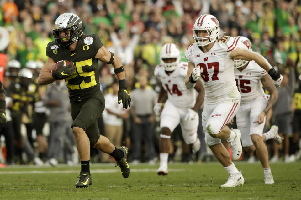 Oregon safety Brady Breeze, left, runs for a touchdown past Wisconsin running back Garrett Groshek after a blocked punt during second half of the Rose Bowl NCAA college football game Wednesday, Jan. 1, 2020, in Pasadena, Calif. (AP Photo/Marcio Jose Sanchez)