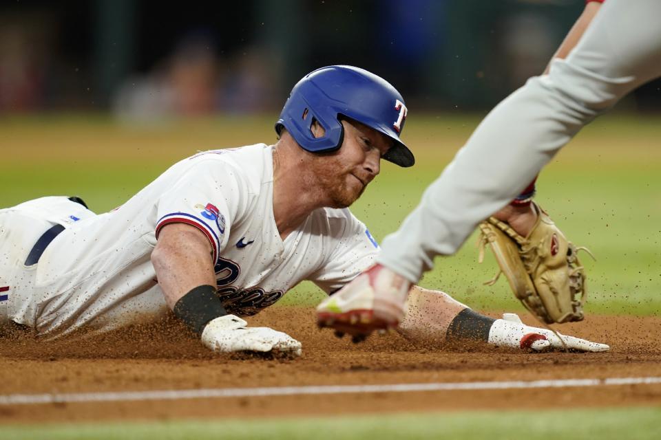 Texas Rangers' Kole Calhoun is tagged out by Philadelphia Phillies third baseman Alec Bohm, right, as Calhoun tried to reached third on a run-scoring double in the fifth inning of a baseball game, Wednesday, June 22, 2022, in Arlington, Texas. Adolis Garcia scored on the play. (AP Photo/Tony Gutierrez)