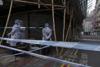 Government workers wearing personal protective equipment stand guard at the closed area in Jordan district, in Hong Kong, Sunday, Jan. 24, 2021. Thousands of Hong Kong residents were locked down Saturday in an unprecedented move to contain a worsening outbreak in the city, authorities said. (AP Photo/Vincent Yu)