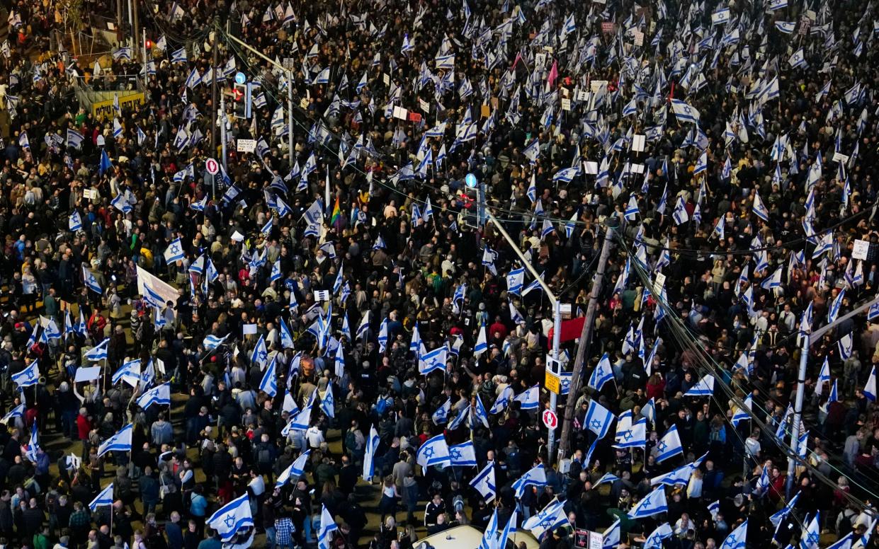 Large crowd holding Israeli flags - Tsafrir Abayov/AP Photo