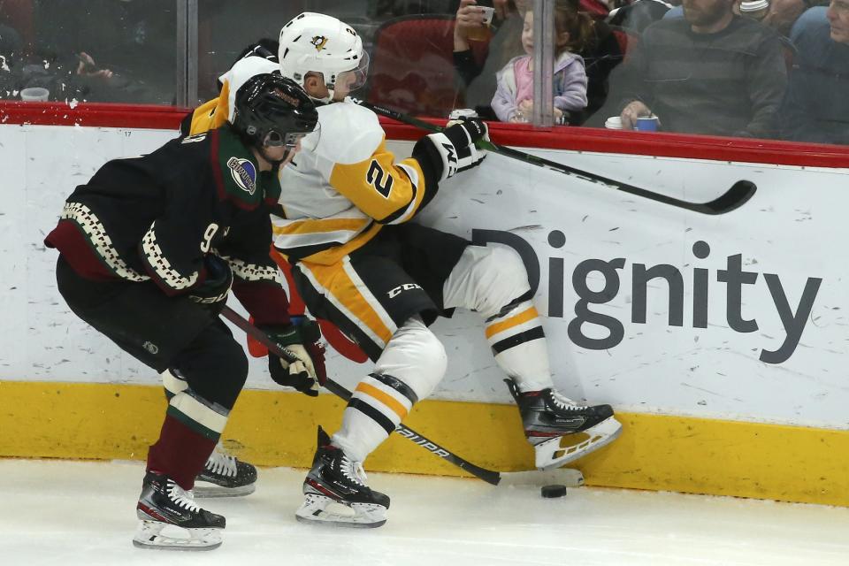 Arizona Coyotes right wing Clayton Keller (9) checks Pittsburgh Penguins defenseman Chad Ruhwedel (2) into the boards as the two battle for the puck during the first period of an NHL hockey game Sunday, Jan. 12, 2020, in Glendale, Ariz. (AP Photo/Ross D. Franklin)