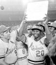 FILE - St. Louis Cardinals shortstop Lou Brock is surrounded by teammates as he holds second base after breaking Ty Cobb's all-time record of 892 stolen bases during a game against the San Diego Padres in San Diego, Calif., in this Monday night, Aug. 29, 1977, file photo. At left is team manager Vern Rapp. The list is disquieting in its length - those from the ranks of 1970s baseball rosters who have died in the past year alone. (AP Photo/File)