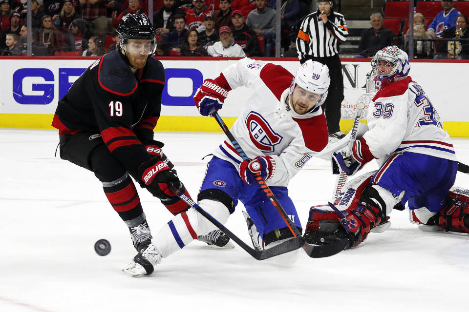 Montreal Canadiens' Tomas Tatar (90), of Slovakia, clears the puck in front of Carolina Hurricanes' Dougie Hamilton (19) during the second period of an NHL hockey game in Raleigh, N.C., Tuesday, Dec. 31, 2019. (AP Photo/Karl B DeBlaker)