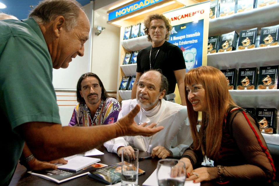 Claude Vorilhon and Brigitte Boisselier, the then-director of Clonaid, listen to an unidentified man on 23 March 2003 , in  São Paulo, during the debut of the Raelian book ‘Yes to Human Cloning’ in Portuguese (MAURICIO LIMA/AFP via Getty Images)