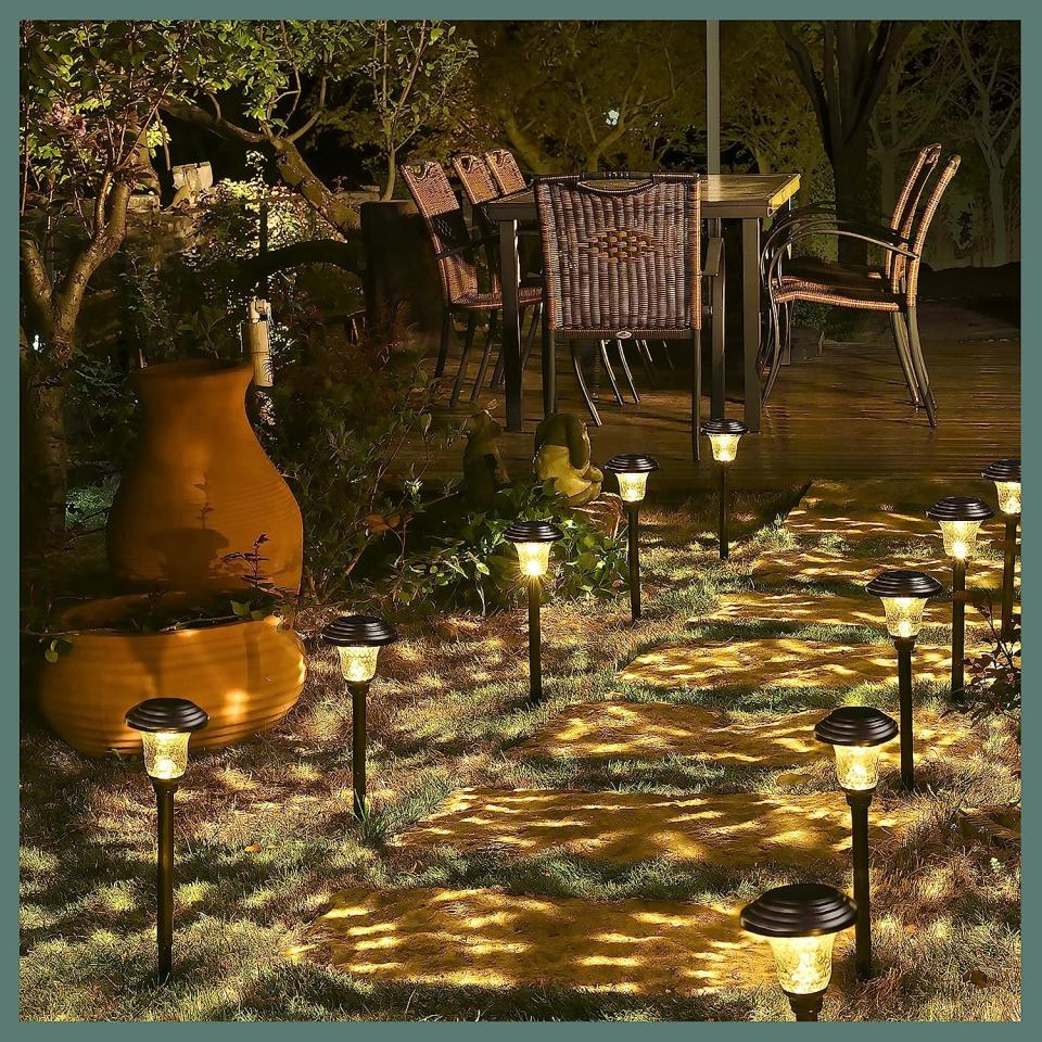 Backyard stone pathway lit by small path lights leading to a furnished patio