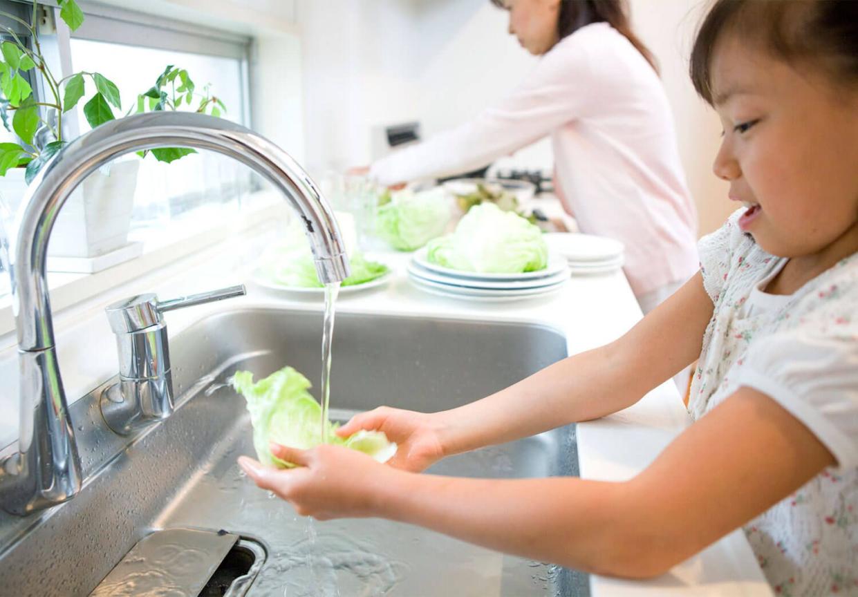 girl helping mom washing lettuce in the kitchen