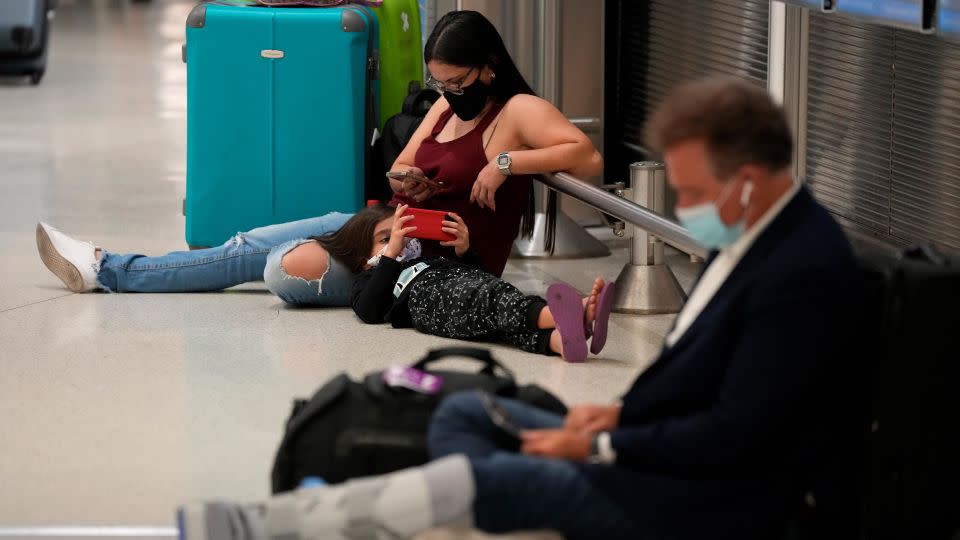 A woman and child wait for their flight alongside another traveler at Miami International Airport on December 27, 2021. - Rebecca Blackwell/AP