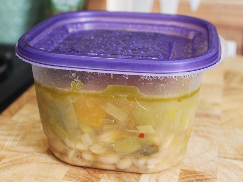 white bean soup in a tupperware container with a purple lid